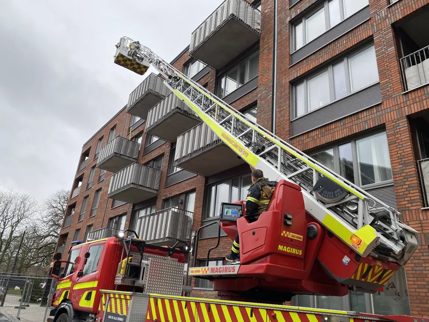 Korg på räddningstjänstens stegbil mot balkong på flerbostadshus