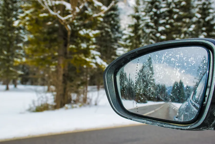 vinterlandskap som syns i sidospegel på bil