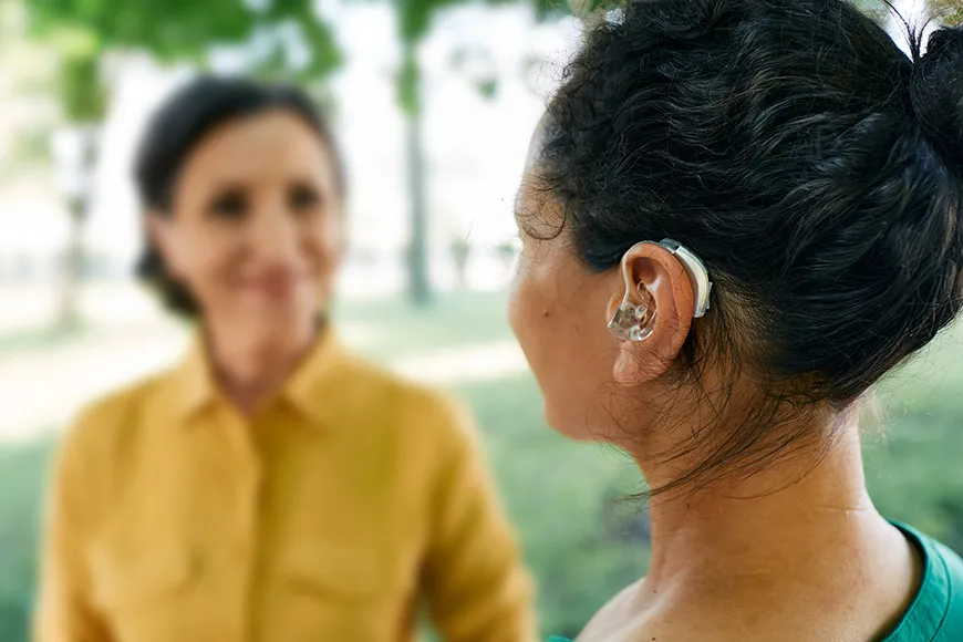 Person med hörapparat ser på en annan person