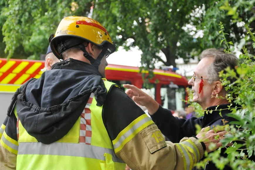 Brandman lyssnar på skadad person som pekar mot en brandbil