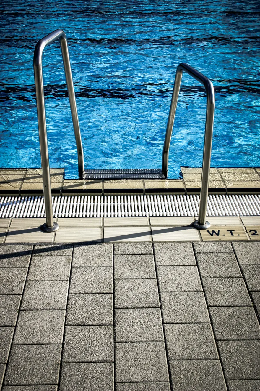 Stege i stål som leder ner till en pool med simbanor